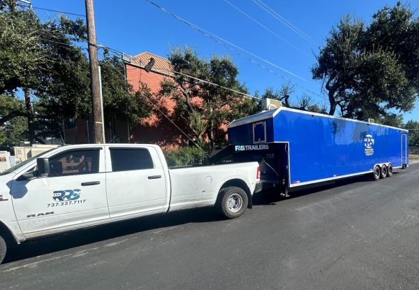 A truck towing a large blue mobile kitchen trailer.