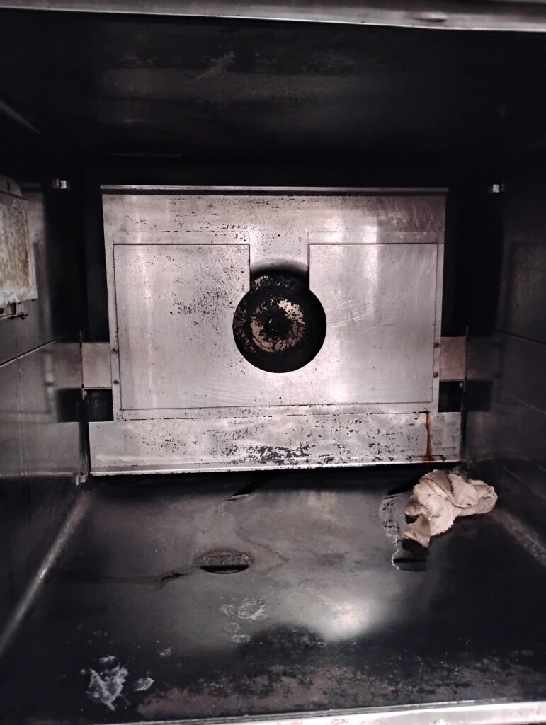 Grease and soot buildup inside neglected commercial kitchen appliance interior