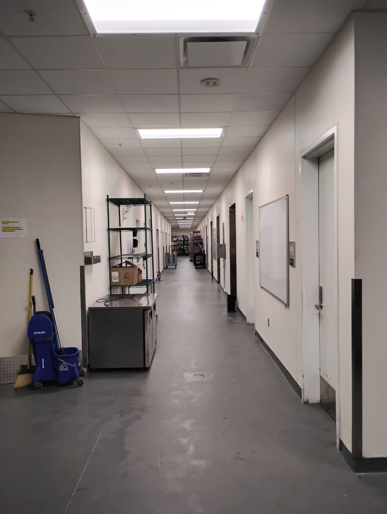 Cleaning cart and supplies staged in a commercial kitchen corridor