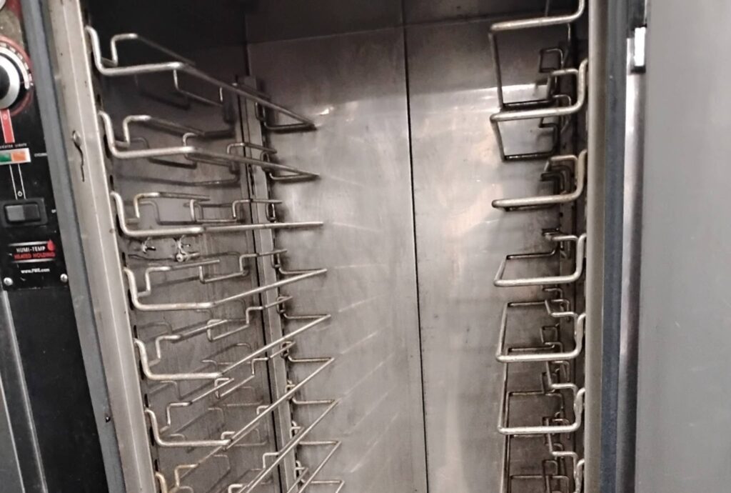 Interior of commercial kitchen holding cabinet with cleaning racks