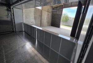 Inside a container concession stand with a stainless steel counter and open service window