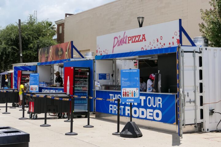 Row of branded container concession stands with queue lines at a festival
