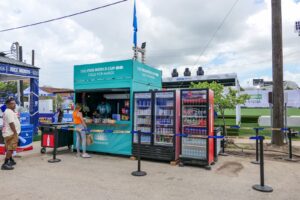 Teal container bar with beverage coolers and queue lines at a fan festival